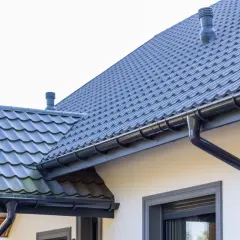 Szary dach z dachówki ceramicznej, rynny i kominek. Sprawdź, jaka jest dachówka ceramiczna cena za m2.