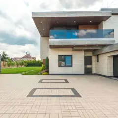 Nowoczesny dom z tarasem nad garażem, podjazdem z kostki brukowej i zadbanym ogrodem.