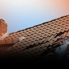 Uszkodzony dach po wichurze, widoczna obróbka dachu wiatrownica i zerwane dachówki.