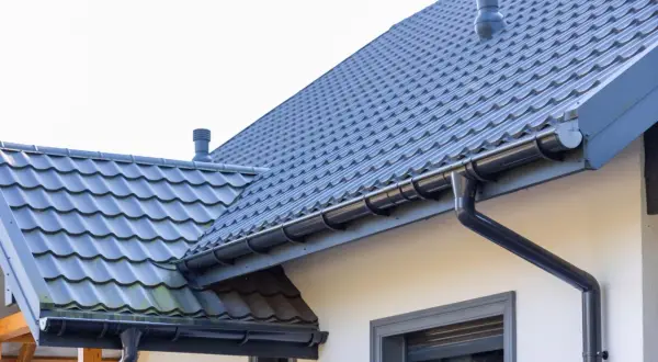 Szary dach z dachówki ceramicznej, rynny i kominek. Sprawdź, jaka jest dachówka ceramiczna cena za m2.