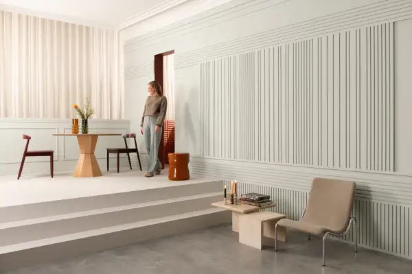 Elegancka kobieta wchodzi do salonu z nowoczesną lamperią. Wnętrze zdobią minimalistyczne meble i subtelne dekoracje.
