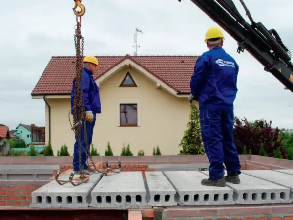 Pracownicy montują prefabrykowane płyty, prezentując różne rodzaje stropów. Budowa domu z wykorzystaniem nowoczesnych technologii.
