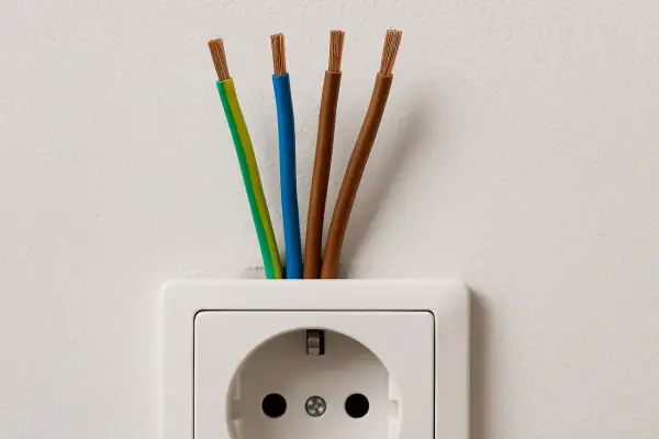 Cztery przewody wychodzące z białego gniazdka elektrycznego. Zastanawiasz się, jaki kabel do gniazdek?
